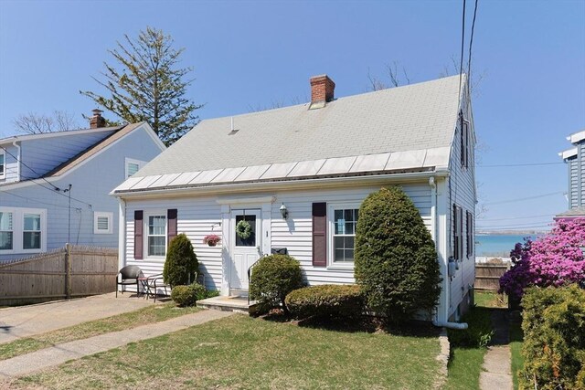 view of front of property with fence, a chimney, a patio area, and a front lawn