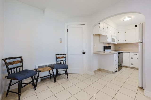 kitchen featuring white appliances, arched walkways, light countertops, white cabinetry, and baseboards