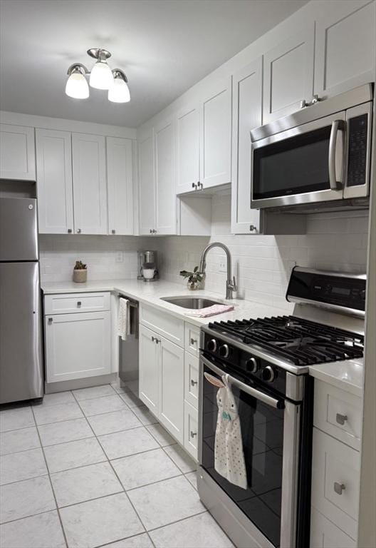 kitchen featuring stainless steel appliances, light countertops, a sink, and tasteful backsplash