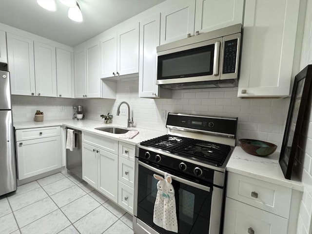 kitchen with stainless steel appliances, backsplash, a sink, and white cabinets