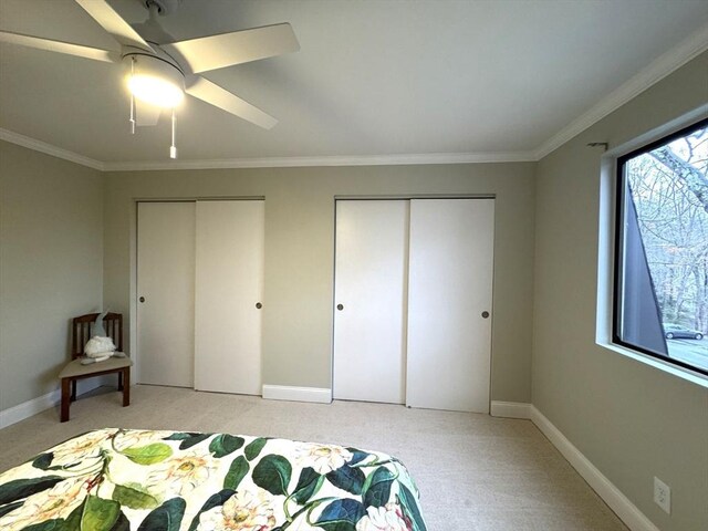 bedroom featuring light carpet, baseboards, ornamental molding, and multiple closets