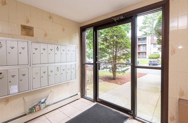 entryway with light tile patterned floors, mail area, a baseboard radiator, and tile walls