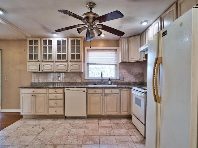 kitchen with dark countertops, backsplash, light brown cabinets, white appliances, and a sink