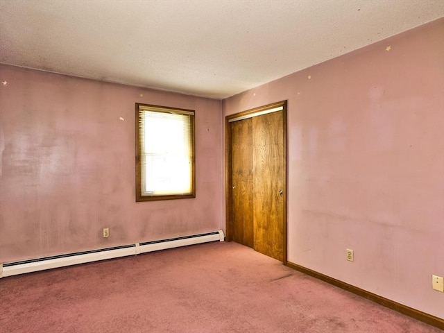 spare room featuring a baseboard radiator, carpet floors, and baseboards