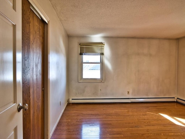 empty room with a baseboard radiator, wood-type flooring, a textured ceiling, and baseboards