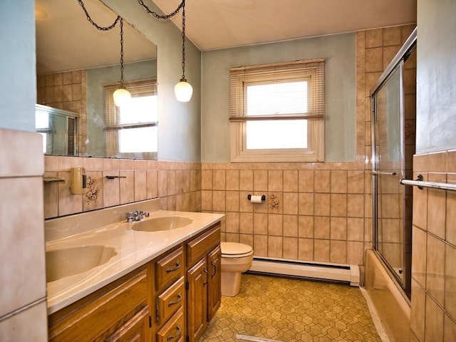 bathroom with a sink, a baseboard radiator, tile walls, and a healthy amount of sunlight