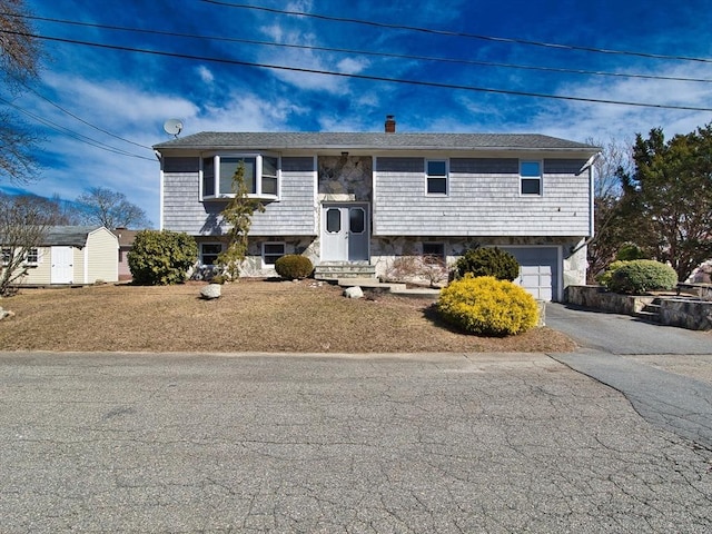 bi-level home featuring an attached garage, a chimney, driveway, and entry steps