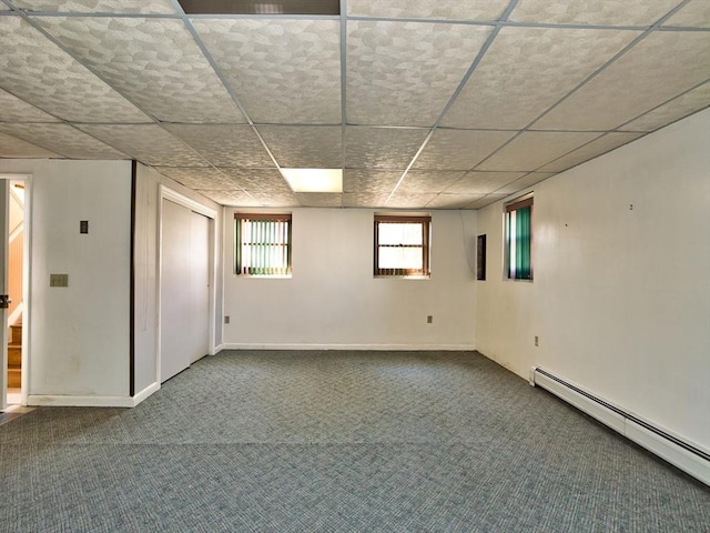 basement with a paneled ceiling, a baseboard heating unit, baseboards, and carpet