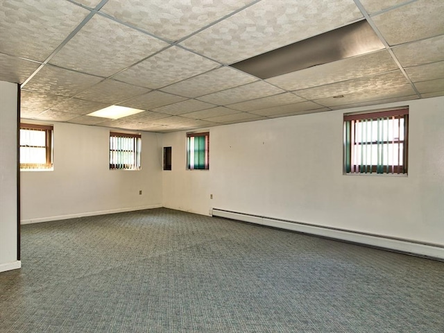 below grade area featuring a baseboard heating unit, carpet, baseboards, and a paneled ceiling