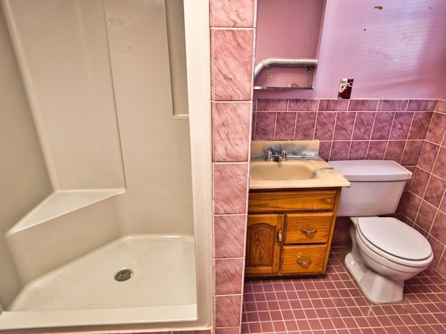 bathroom with vanity, a shower stall, tile walls, toilet, and tile patterned floors