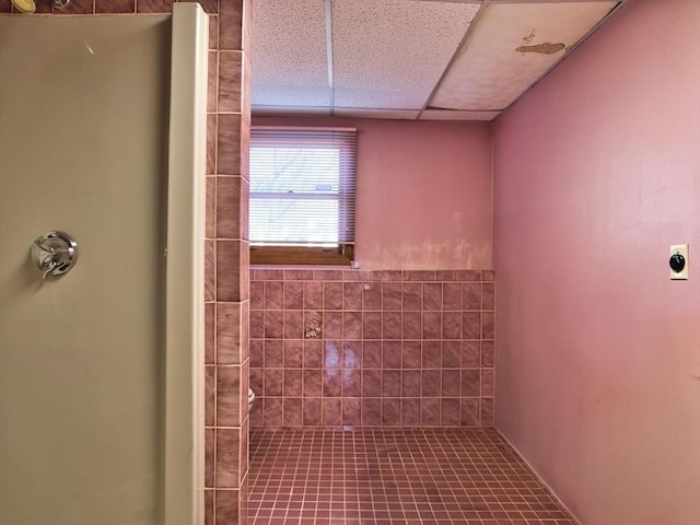 full bath with a drop ceiling and tiled shower