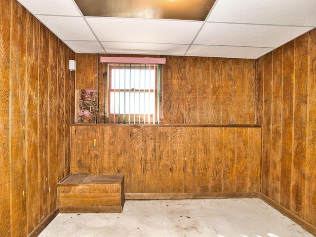 below grade area featuring a drop ceiling and wooden walls