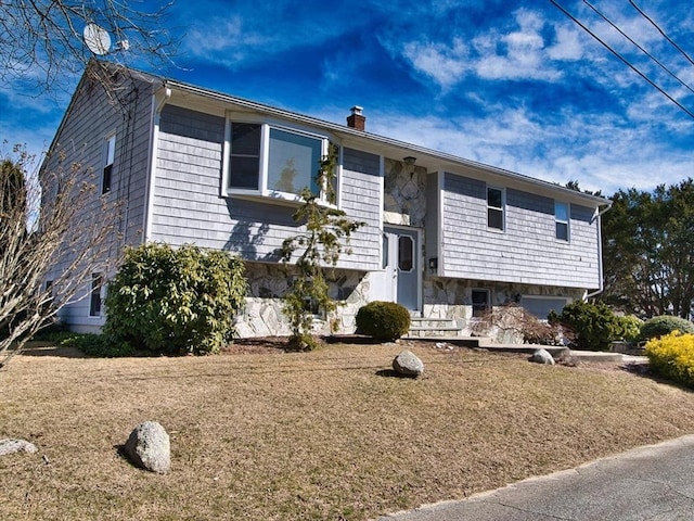 split foyer home with stone siding and a chimney