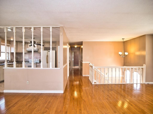 interior space with baseboards, an upstairs landing, hardwood / wood-style flooring, a notable chandelier, and a textured ceiling