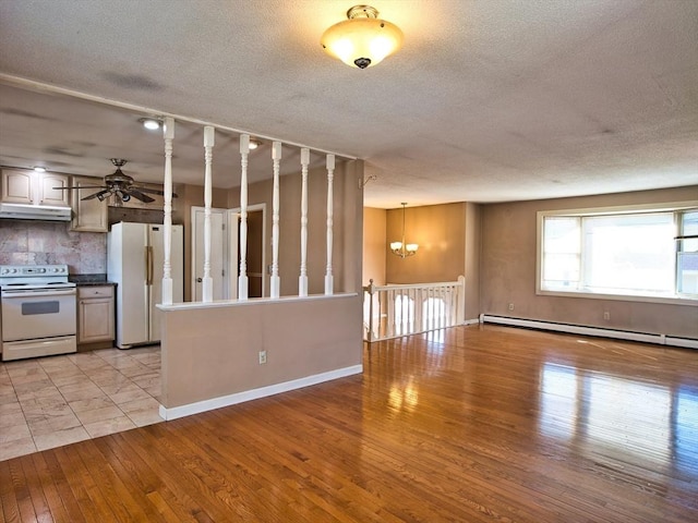 interior space with tasteful backsplash, under cabinet range hood, ceiling fan with notable chandelier, light wood-style flooring, and white appliances