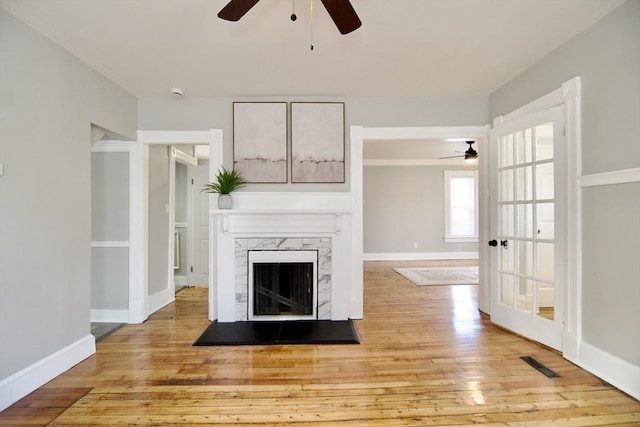 unfurnished living room with ceiling fan, light hardwood / wood-style flooring, and a high end fireplace