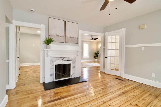 unfurnished living room featuring a fireplace, ceiling fan, and light wood-type flooring