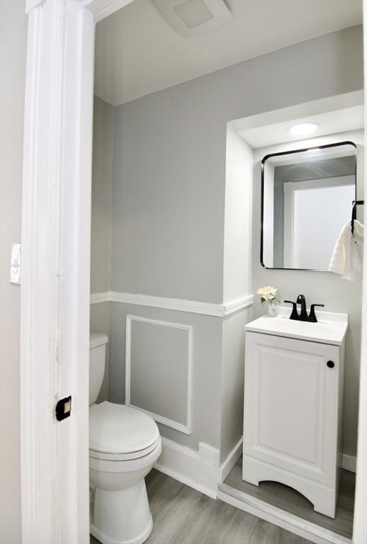 bathroom with vanity, toilet, and hardwood / wood-style floors