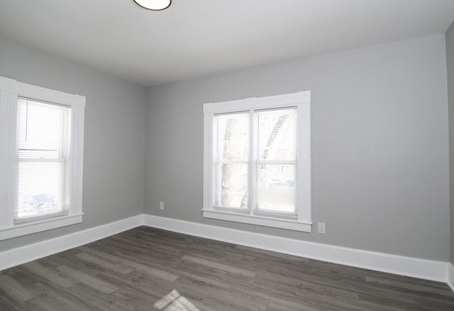 empty room featuring a wealth of natural light and dark wood-type flooring