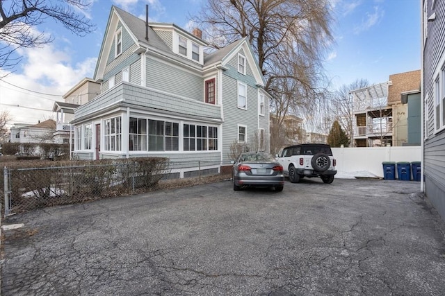 view of side of home with fence and a chimney