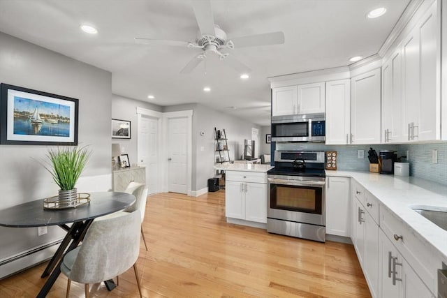 kitchen with stainless steel appliances, light wood-style floors, a peninsula, and white cabinets