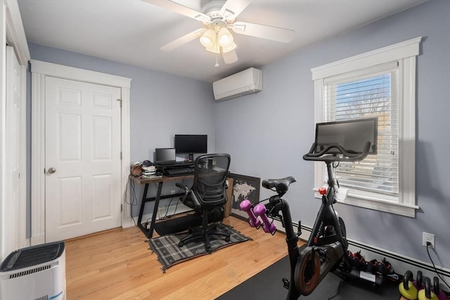 workout room featuring a ceiling fan, a wall unit AC, and wood finished floors