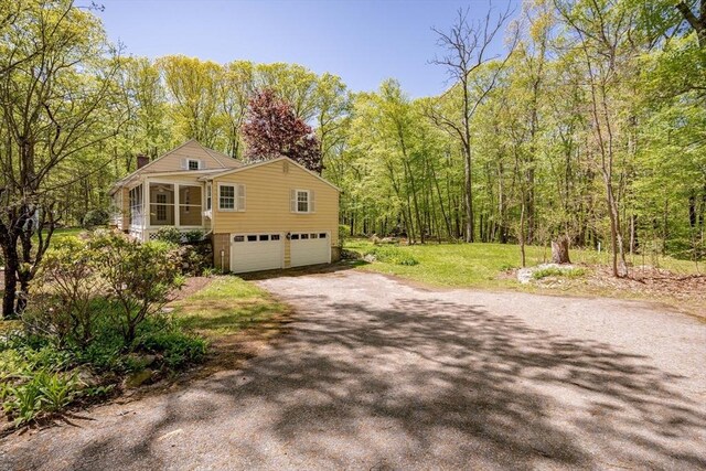 313 Bennett Rd, Hampden, MA 01036 - view of side of home featuring a garage, a sunroom, dirt driveway, a chimney, and a wooded view