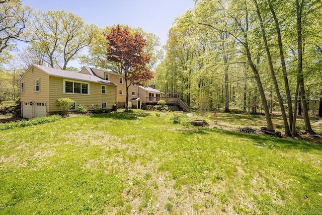 313 Bennett Rd, Hampden, MA 01036 - view of grassy yard featuring an attached garage, a wooden deck, and an outdoor fire pit