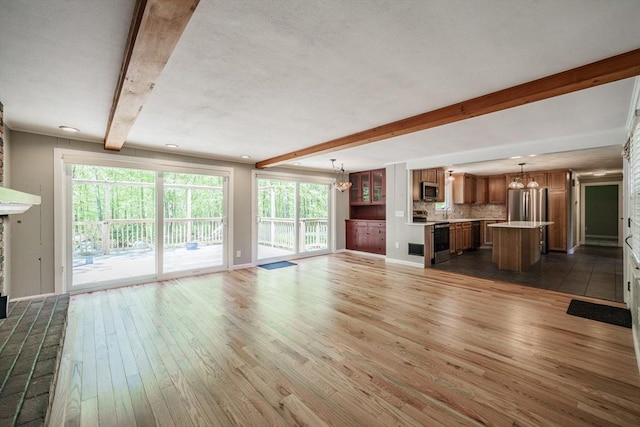 313 Bennett Rd, Hampden, MA 01036 - unfurnished living room featuring a chandelier, beam ceiling, wood finished floors, a brick fireplace, and a sink