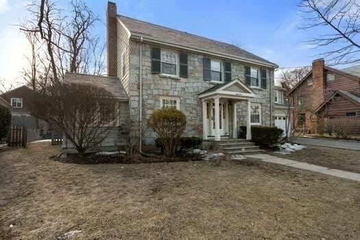 colonial house featuring stone siding and a chimney