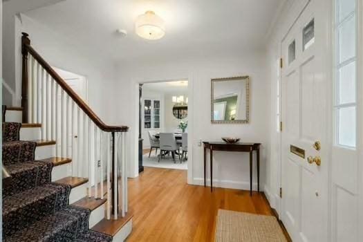 entryway with a chandelier, light wood finished floors, and stairway