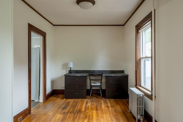 unfurnished office featuring radiator heating unit, ornamental molding, wood finished floors, plenty of natural light, and baseboards