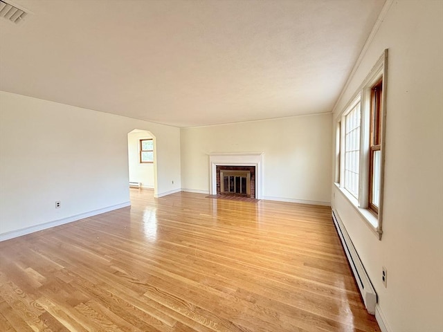 unfurnished living room with baseboard heating, light hardwood / wood-style floors, and a brick fireplace