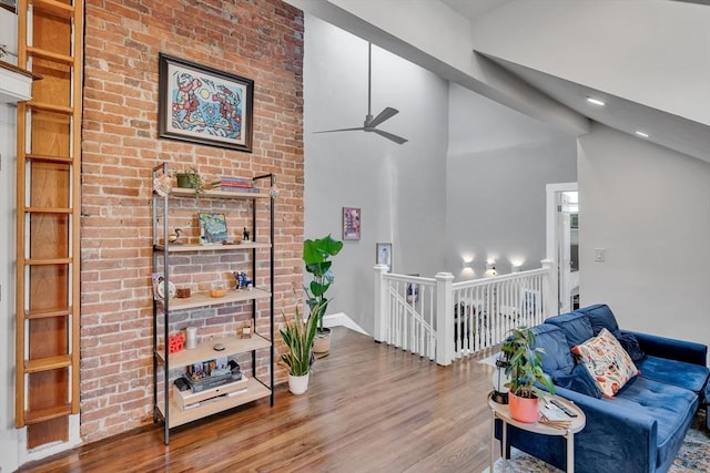 living room with ceiling fan, wood-type flooring, and lofted ceiling