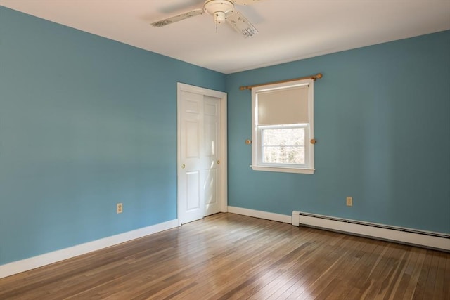 empty room with a ceiling fan, wood-type flooring, baseboards, and baseboard heating