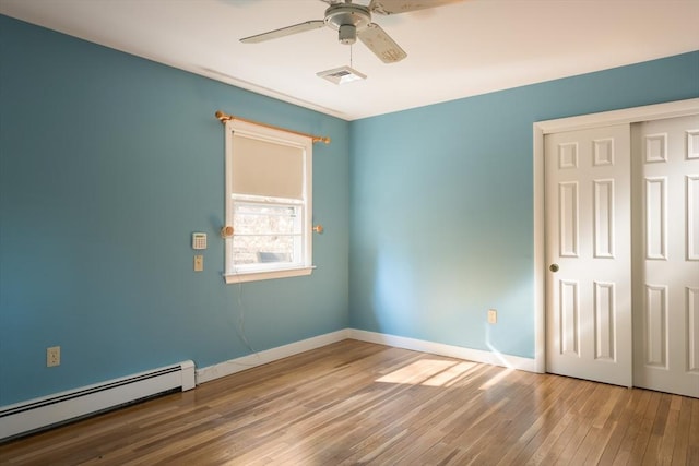 spare room with a ceiling fan, visible vents, baseboards, baseboard heating, and hardwood / wood-style floors