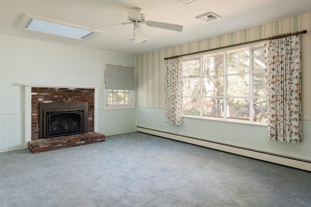 unfurnished living room with visible vents, ceiling fan, baseboard heating, carpet floors, and a brick fireplace