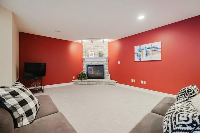 living room with rail lighting, light carpet, and a fireplace