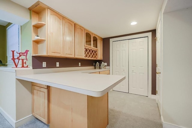 kitchen featuring light brown cabinetry, kitchen peninsula, and light carpet