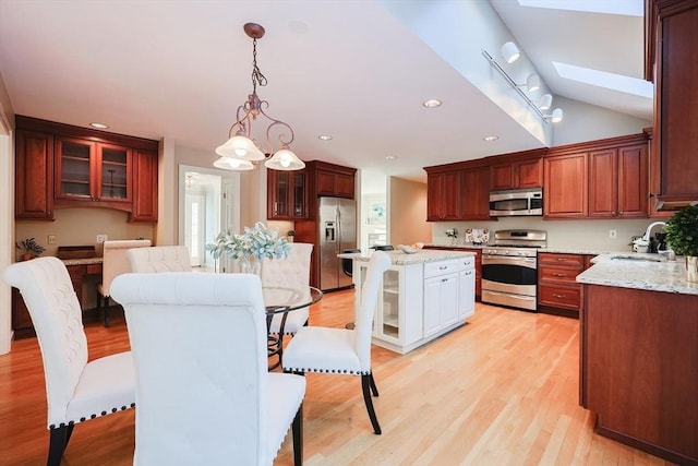 kitchen with sink, decorative light fixtures, a center island, light wood-type flooring, and appliances with stainless steel finishes