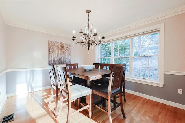 dining area with ornamental molding, a chandelier, and light wood-type flooring