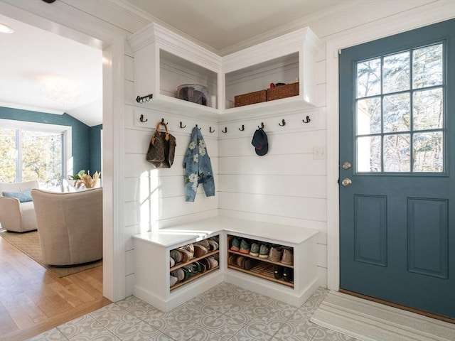 mudroom with light hardwood / wood-style flooring, ornamental molding, and vaulted ceiling