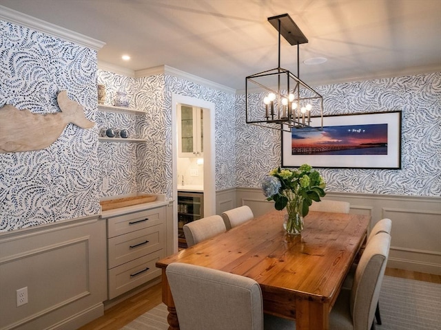 dining space featuring an inviting chandelier, crown molding, wine cooler, and wood-type flooring