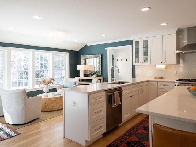 kitchen with stainless steel dishwasher, sink, white cabinetry, light wood-type flooring, and range