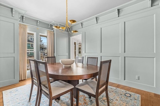 dining room with crown molding, light hardwood / wood-style flooring, and a notable chandelier