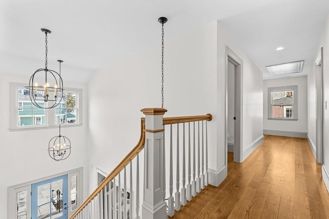 corridor with an inviting chandelier, vaulted ceiling, and hardwood / wood-style floors