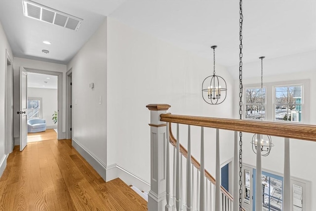 hall featuring plenty of natural light, light hardwood / wood-style floors, and a chandelier