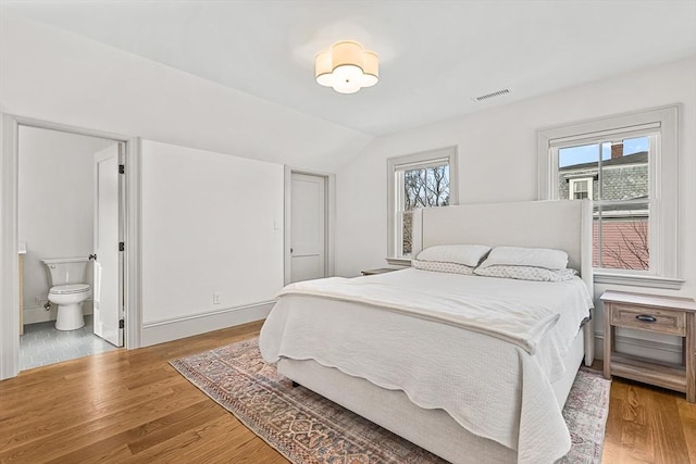 bedroom featuring multiple windows, lofted ceiling, and light hardwood / wood-style flooring