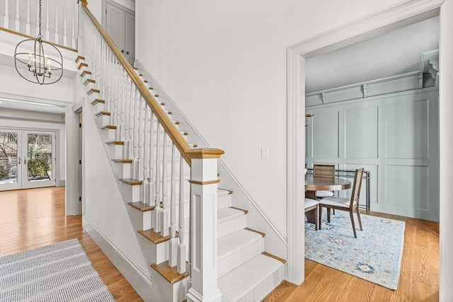 stairs with an inviting chandelier, hardwood / wood-style flooring, french doors, and a towering ceiling