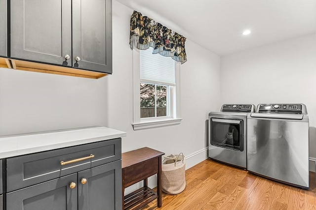 laundry room featuring cabinets, washer and dryer, and light hardwood / wood-style flooring